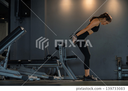 Fitness asian woman doing exercise and lifting dumbbells weights at sport gym. 139733083