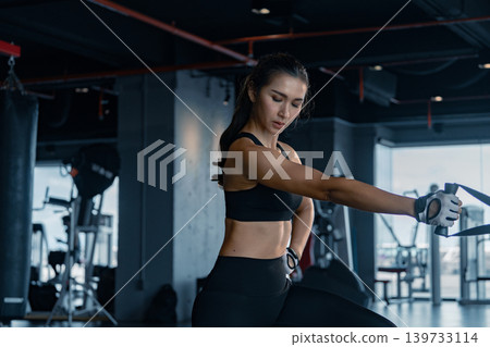 Sporty woman exercising on multistation at gym for arm and shoulders muscles. Fitness exercising in gym. Sporty woman exercising on multistation at gym for arm and shoulders muscles. Fitness exercising in gym. 139733114