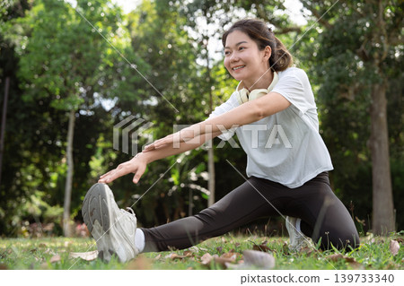 Young Asian woman doing stretches before exercising or training in a park before training, enjoying a healthy lifestyle. Young Asian woman doing stretches before exercising or training in a park before training, enjoying a healthy lifestyle. 139733340