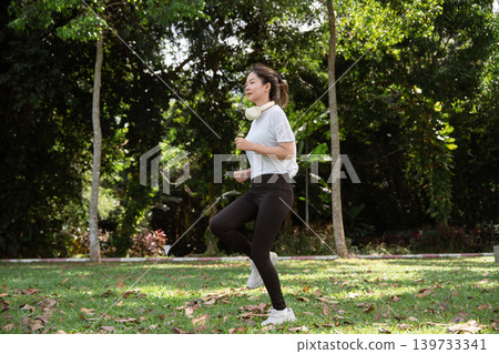 Young Asian woman doing stretches before exercising or training in a park before training, enjoying a healthy lifestyle. Young Asian woman doing stretches before exercising or training in a park before training, enjoying a healthy lifestyle. 139733341
