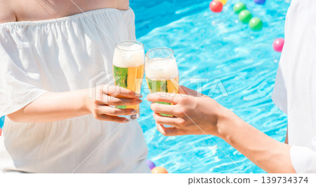 Couple toasting with beer glasses by the pool at a vacation resort hotel Couple toasting with beer glasses by the pool at a vacation resort hotel 139734374