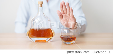 Man making stop hand gesture to refuse a glass of Cognac, Healthy man say no to alcohol drink, stop alcoholism and addiction concept. Responsible man reject a drink before driving and quit booze Man making stop hand gesture to refuse a glass of Cognac, Healthy man say no to alcohol drink, stop alcoholism and addiction concept. Responsible man reject a drink before driving and quit booze 139734504