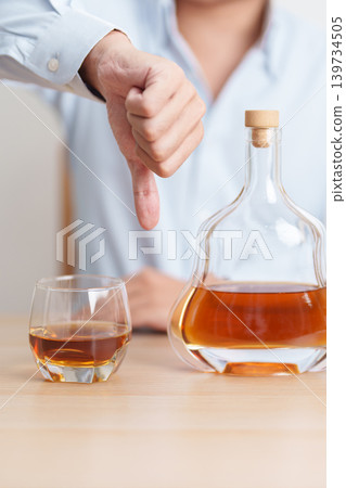 Man making thumb down hand gesture to refuse a glass of Cognac, Healthy man say no to alcohol drink, stop alcoholism and addiction concept. Responsible man reject a drink before driving and quit booze Man making thumb down hand gesture to refuse a glass of Cognac, Healthy man say no to alcohol drink, stop alcoholism and addiction concept. Responsible man reject a drink before driving and quit booze 139734505