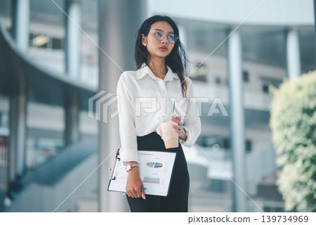 Professional woman in eyeglasses holding iced coffee and a business report in a modern office, representing calm confidence, corporate lifestyle, work routine, and everyday productivity. 139734969