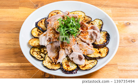 Grilled eggplant topped with pork shabu-shabu, placed on a wooden table. Grilled eggplant topped with pork shabu-shabu, placed on a wooden table. 139735494