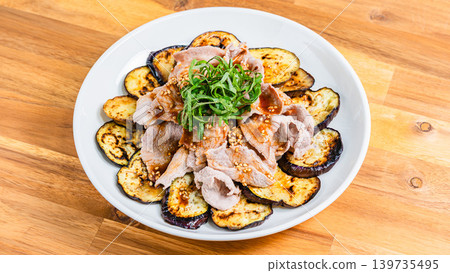 Grilled eggplant topped with pork shabu-shabu, placed on a wooden table. Grilled eggplant topped with pork shabu-shabu, placed on a wooden table. 139735495