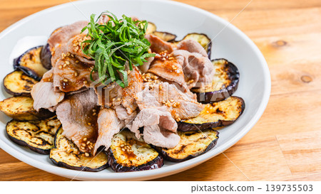 Grilled eggplant topped with pork shabu-shabu, placed on a wooden table. Grilled eggplant topped with pork shabu-shabu, placed on a wooden table. 139735503