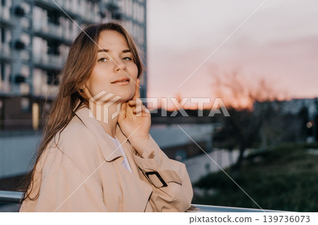 Woman sunset city portrait of a young elegant woman wearing a beige trench coat standing outdoors during golden hour with copy space Woman sunset city portrait of a young elegant woman wearing a beige trench coat standing outdoors during golden hour with copy space 139736073