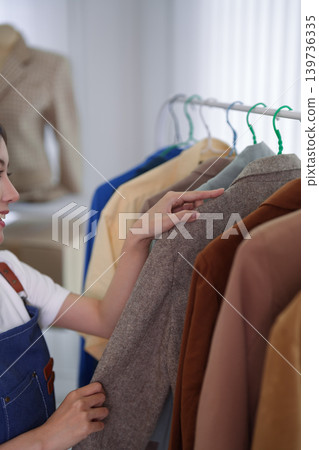 Asian women online merchant live streaming fashion clothing selection for ecommerce social media business selling apparel product showcase from home studio Asian women online merchant live streaming fashion clothing selection for ecommerce social media business selling apparel product showcase from home studio 139736335