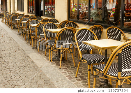 Empty street cafe tables and chairs in a row along a parisian sidewalk, representing travel and european culture 139737294