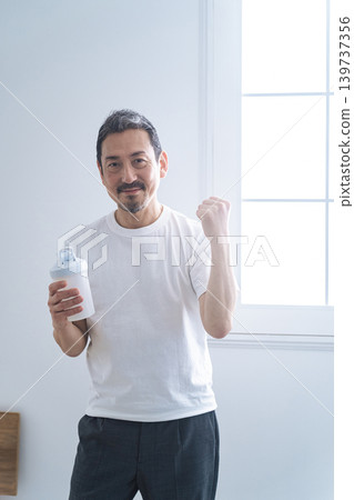 A middle-aged man holding a protein bottle. A middle-aged man holding a protein bottle. 139737356