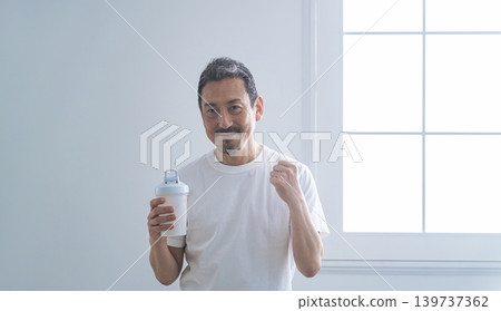 A middle-aged man holding a protein bottle. A middle-aged man holding a protein bottle. 139737362