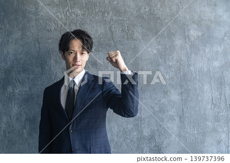 A young male businessperson makes a victory pose. A young male businessperson makes a victory pose. 139737396