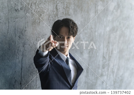 A young male businessperson points upwards. A young male businessperson points upwards. 139737402