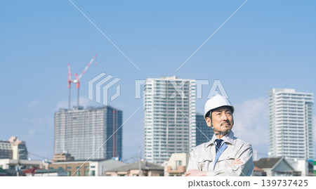 A male worker gazes into the distance in front of a city. A male worker gazes into the distance in front of a city. 139737425