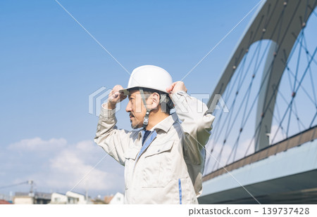A male worker gazes into the distance from the bridge. A male worker gazes into the distance from the bridge. 139737428