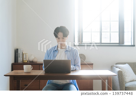 一個男人在房間裡使用筆記本電腦 139737448