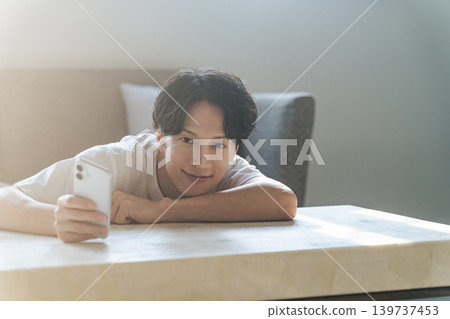 一個男人面帶微笑地使用智慧型手機。 139737453