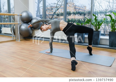 Woman Performing Dynamic Yoga Stretch In Studio Woman Performing Dynamic Yoga Stretch In Studio 139737490