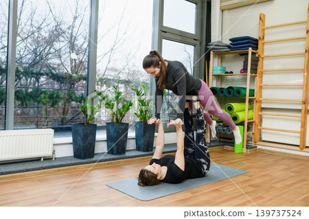Women Practicing Acro Yoga In Fitness Studio Women Practicing Acro Yoga In Fitness Studio 139737524