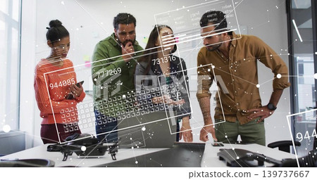 Reviewing team of six inspecting table in office, wearing jackets, with drone, laptop and overlays Reviewing team of six inspecting table in office, wearing jackets, with drone, laptop and overlays 139737667