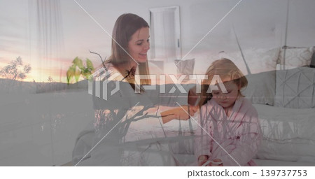 Smiling mother and daughter sitting on bed in home bedroom, with pink bathrobe and sunset overlay Smiling mother and daughter sitting on bed in home bedroom, with pink bathrobe and sunset overlay 139737753