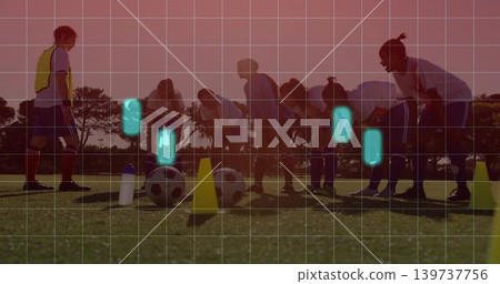 Practicing team and coach stretching on grassy pitch at sunset, with balls, cones, yellow bib, grid Practicing team and coach stretching on grassy pitch at sunset, with balls, cones, yellow bib, grid 139737756