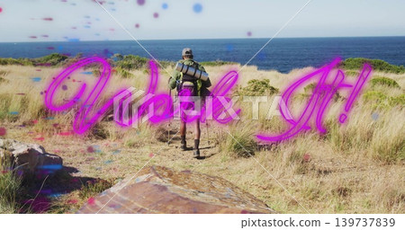 Walking male hiker on coast path to ocean with backpack rolled-pad poles cap neon-pink 'Walk It!' Walking male hiker on coast path to ocean with backpack rolled-pad poles cap neon-pink 'Walk It!' 139737839