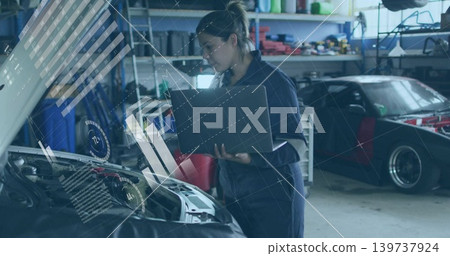 Checking woman tech viewing engine data with laptop in garage, wearing navy coverall HUD overlays Checking woman tech viewing engine data with laptop in garage, wearing navy coverall HUD overlays 139737924