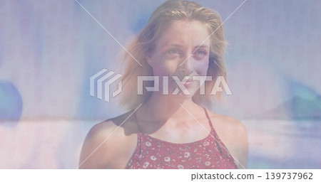 Smiling woman facing right, wearing red floral sleeveless dress at shoreline, blonde hair Smiling woman facing right, wearing red floral sleeveless dress at shoreline, blonde hair 139737962