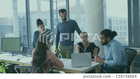 Reviewing five colleagues in business casual examining laptop and blueprints at office windows 139738064