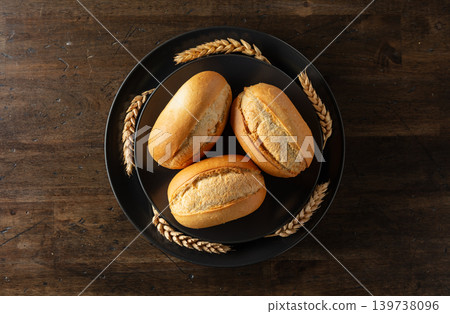 French buns and wheat ears on a black plate. French buns and wheat ears on a black plate. 139738096