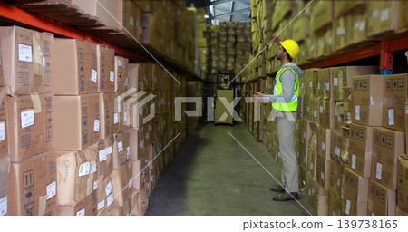 Inspecting worker in hard hat neon vest reaching shelf at warehouse with scanner, boxes, copy space Inspecting worker in hard hat neon vest reaching shelf at warehouse with scanner, boxes, copy space 139738165
