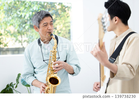 一位家長和孩子正在演奏樂器:薩克斯風和貝斯即興演奏。 一位家長和孩子正在演奏樂器:薩克斯風和貝斯即興演奏。 139738230