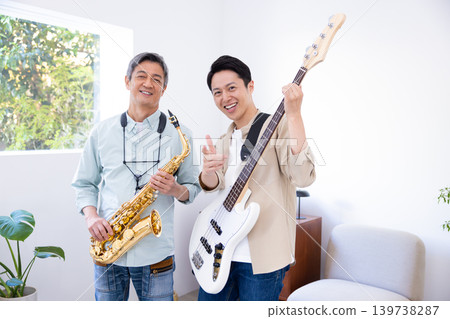 A parent and child playing musical instruments: a saxophone and bass jam session. 139738287