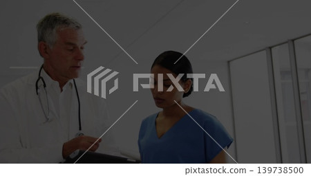 Showing doctor and nurse reviewing tablet in clinic hall, lab coat, blue scrubs, stethoscope Showing doctor and nurse reviewing tablet in clinic hall, lab coat, blue scrubs, stethoscope 139738500