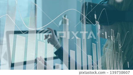 Analyzing blazer-wearing analyst touching tablet at desk, with financial chart overlay and headset Analyzing blazer-wearing analyst touching tablet at desk, with financial chart overlay and headset 139738607