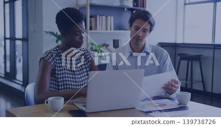 Discussing woman checked dress man light blue shirt reviewing laptop and color charts office table Discussing woman checked dress man light blue shirt reviewing laptop and color charts office table 139738726