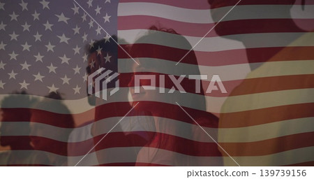 Watching group of adults standing behind sheer American flag at sunset, wearing casual clothes Watching group of adults standing behind sheer American flag at sunset, wearing casual clothes 139739156