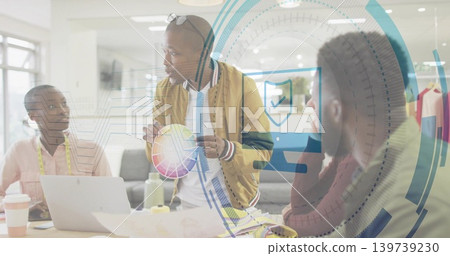 Presenting man in tan jacket holding color wheel and speaking at studio, with laptop and swatches Presenting man in tan jacket holding color wheel and speaking at studio, with laptop and swatches 139739230