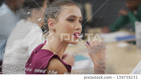 Speaking woman in magenta sleeveless blouse holding pen by face at meeting table, dotted overlay Speaking woman in magenta sleeveless blouse holding pen by face at meeting table, dotted overlay 139739231