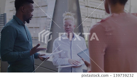 Central-albinism-man with white-shirt and teal-pink-team discussing papers and tablet at atrium Central-albinism-man with white-shirt and teal-pink-team discussing papers and tablet at atrium 139739232