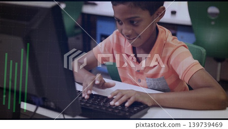 Typing boy in orange-striped polo leaning in school computer lab, using black keyboard and monitor Typing boy in orange-striped polo leaning in school computer lab, using black keyboard and monitor 139739469