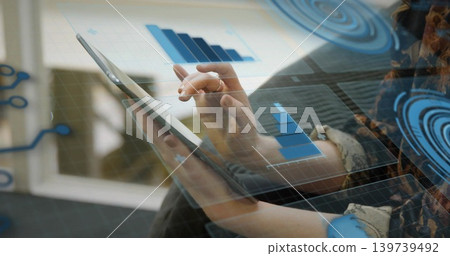Tapping woman wearing patterned long-sleeve top holding tablet on sofa by window, with HUD charts Tapping woman wearing patterned long-sleeve top holding tablet on sofa by window, with HUD charts 139739492