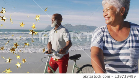 Riding mature couple wearing casual clothes cycling along sandy beach, with bicycles and gold stars Riding mature couple wearing casual clothes cycling along sandy beach, with bicycles and gold stars 139739499