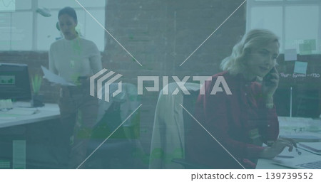 Speaking mid-adult woman wearing red blouse, using handset and typing at open-plan desk, copy space Speaking mid-adult woman wearing red blouse, using handset and typing at open-plan desk, copy space 139739552
