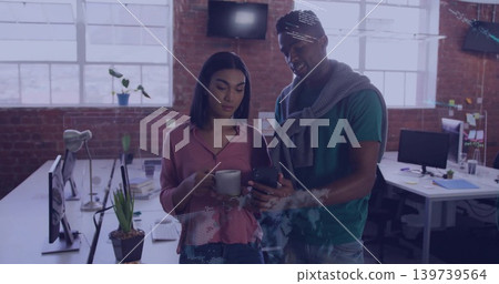 Showing smartphone, woman pink blouse holding mug while man in green tee viewing screens loft Showing smartphone, woman pink blouse holding mug while man in green tee viewing screens loft 139739564