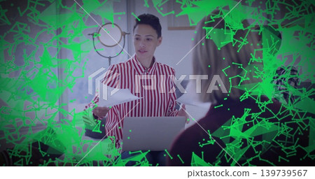 Presenting woman in red-striped shirt leading meeting at table with laptop, papers, green overlay Presenting woman in red-striped shirt leading meeting at table with laptop, papers, green overlay 139739567