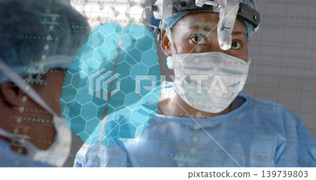 Operating surgeon with headlight, mask and blue gown performing surgery in OR, showing hex overlay Operating surgeon with headlight, mask and blue gown performing surgery in OR, showing hex overlay 139739803