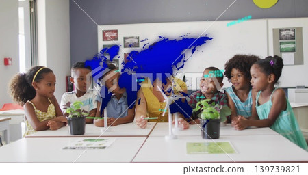 Leading teacher in yellow top leaning forward, handling turbine model at school table, with plants Leading teacher in yellow top leaning forward, handling turbine model at school table, with plants 139739821